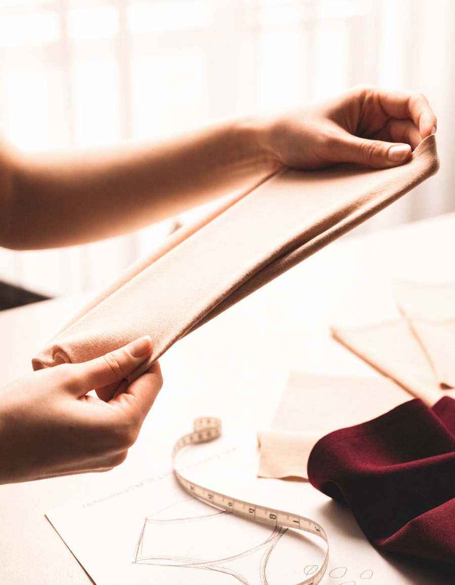 Coulisses de conception : mains testant l'élasticité d'un tricot nude, croquis techniques